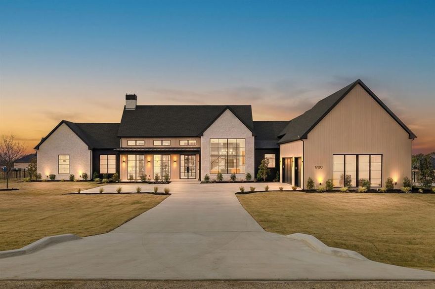 Where modern farmhouse elegance meets elevated luxury, this stunning custom estate—masterfully built by Budz Custom Homes—offers an extraordinary lifestyle on just over an acre. Framed by soaring glass windows that flood the home with natural light, every inch reflects refined craftsmanship, designer finishes, and an elevated attention to detail rarely seen at this level. The open, airy layout is designed for effortless entertaining, featuring expansive living and dining spaces anchored by floor-to-ceiling windows. The gourmet kitchen is a true showpiece offering a full prep kitchen and oversized pantry, making hosting both seamless and sophisticated. The primary suite is a sanctuary unto itself, with a spa-like bathroom boasting luxurious materials, a statement soaking tub, an oversized walk-in shower, and elevated lighting that brings restoration. The custom closet is beautifully appointed with detailed built-ins, a central storage island, and a library-style ladder system that glides around the perimeter—perfect for reaching the upper display cabinetry and maximizing every inch of space. Upstairs, a thoughtfully added flex area provides endless versatility—ideal for a game room, private office, guest quarters, or media retreat—complete with additional storage and a half bathroom. Outdoors, enjoy a gorgeous front porch and a spacious covered patio overlooking the expansive backyard, complete with a built-in grill for year-round enjoyment. The epoxy-finished garage floors add yet another level of polish to this perfectly curated home. From its architectural presence to its exquisite finish-out, this home embodies modern luxury with the warmth and character of a true custom build—light-filled, sophisticated, and
created for exceptional living.