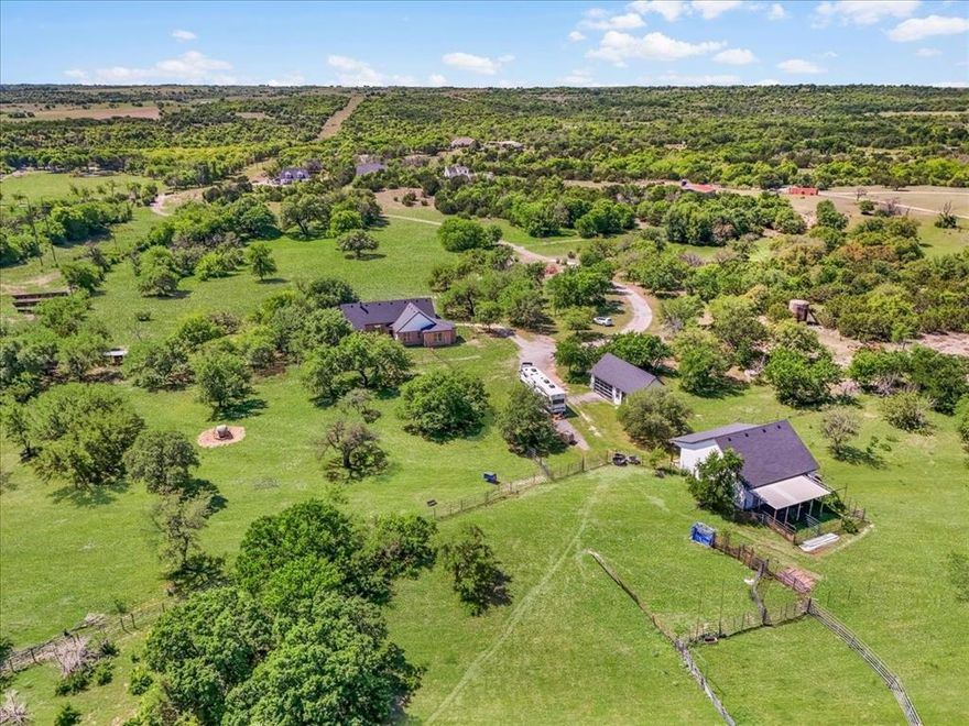 Experience true Texas farm & ranch living with this exceptional 4-bedroom, 2.5-bath, 1.5-story home set on just under 30 acres of beautifully maintained, AG-exempt land. Designed with both comfort and functionality in mind, this property is ideal for cattle, horses, and livestock, featuring lush Coastal Bermuda grass and well-planned cross fencing, including field, barbed, and pipe fencing, all secured by a private gated entry.

Surrounded by rolling hills, mature trees, and abundant wildlife, the home offers peaceful, panoramic views in every direction. Inside, an open floor plan and oversized windows bring the outdoors in. The spacious kitchen includes granite countertops, an electric cooktop & oven, built-in microwave, and a cozy breakfast nook, while the large dining area is perfect for gathering with scenic views. The inviting living room is anchored by a charming wood-burning fireplace.

The private primary suite offers serene views and features an ensuite bath with a garden tub, walk-in shower, and generous walk-in closet. A split-bedroom layout enhances privacy, and the upstairs loft provides flexible space for a playroom, office, storage, or potential 5th bedroom.

Outside, the ranch is fully equipped with a 36x36 shop barn with electric, dual garage doors, partial slab foundation, and three dirt-floor stalls with a covered porch. A large metal building offers additional storage or hay barn use. Entertain or unwind in the 760 sq ft bunkhouse complete with projector, screen, and surround sound, plus a large garage door for seamless indoor-outdoor living.

Additional features include two water wells, aerobic septic system, and paid-off solar panels with battery backup—keeping electric bills impressively low. Not to mention an RV hookup! This is the perfect blend of ranch-ready functionality and modern comfort.