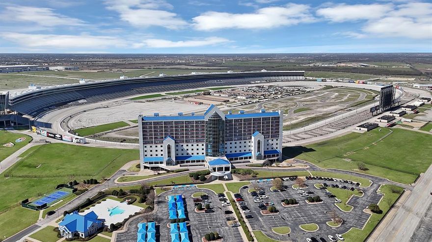 Experience race weekend like never before from your 9th-floor luxury condo overlooking Turn 2 at Texas Motor Speedway. This fully upgraded 2-bed, 2-bath residence was designed for both comfort and unforgettable entertaining. Floor-to-ceiling windows showcase sweeping track views, complete with electric shades. Inside, 14 stadium-style seats line the window, giving you a private, climate-controlled viewing experience unlike anything else at the speedway. The open-concept living area features two oversized bartops perfect for hosting, along with a built-in wine fridge and beverage fridge to keep refreshments flowing all race weekend long. Ownership includes 8 tickets to every race, making this the ultimate motorsports retreat. Just in time for the major NASCAR race weekend in May! Community amenities elevate the lifestyle even further with access to a resort-style Texas-shaped pool, clubhouse, fitness center, tennis court, pickleball court, and basketball court. LIVE ABOVE THE ACTION. ENTERTAIN IN STYLE. OWN THE ROAR...Prefer it turnkey? Furnishings are negotiable.