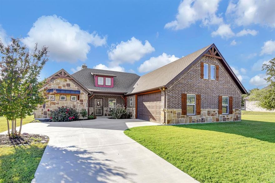 Stunning single-story, like-new custom-built John Schedcik home on 1 acre in highly rated Paradise ISD, offering beautiful wooded views. The exterior boasts striking Oklahoma multicolored cut stone and rock for timeless curb appeal. Inside, the gourmet kitchen features stainless steel appliances, granite countertops, decorative lighting above the island and breakfast nook, and the refrigerator stays. A formal dining room showcases a coordinating chandelier, while the living room highlights tall vaulted ceilings, a floor-to-ceiling stone fireplace, built-in cabinets, and cozy built in seating. The spacious primary suite offers tray ceilings with wood accents, windows for natural light, and a luxurious ensuite with a walk-in shower, freestanding tub with frosted window, dual vanities, built-in cabinetry, and expansive walk-in closet with shelving. Two additional bedrooms provide flexibility for family or guests. Ceramic wood-look tile and carpet flow seamlessly throughout, complemented by energy-efficient argon windows for comfort and savings. The insulated garage adds practicality, and foam installation throughout and installed 31 piers under home during construction based on engineers recommendation. Outdoors, the large backyard features an extended covered patio—perfect for relaxing or entertaining.