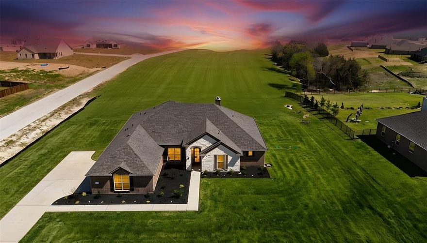 A beautiful stone and brick ranch style home nestled on an acre lot in the growing town of Van Alstyne. Come see this stunning 4-Bedroom  2.5 bath Home with wood look tile throughout, modern light fixtures and premium finishes.The heart of the home features a bright, open kitchen with an oversized island, granite countertops, abundant cabinetry, a large pantry and stainless steel appliances. The Modern kitchen flows into the large  living area, highlighted by a wood-burning fireplace, wood beams  and oversized windows overlooking the backyard. A separate dining room Features  a beautiful  modern chandelier. The private primary suite delivers a spa-like feel with a wall of windows overlooking the backyard, a large walk-in shower , soaking tub , dual vanities and a spacious closet. Three additional bedrooms are separated for comfort and functionality.  A 3-car side entry garage with an extra long driveway offers ample parking, storage, or workshop space. Outdoor living is a standout with an expansive covered patio and fireplace—perfect for entertaining, grilling, or simply enjoying the scenic views, peaceful vibes, and wide-open space. Information is deemed reliable but not guaranteed, buyer and buyer's agent to ensure proper due diligence is completed.