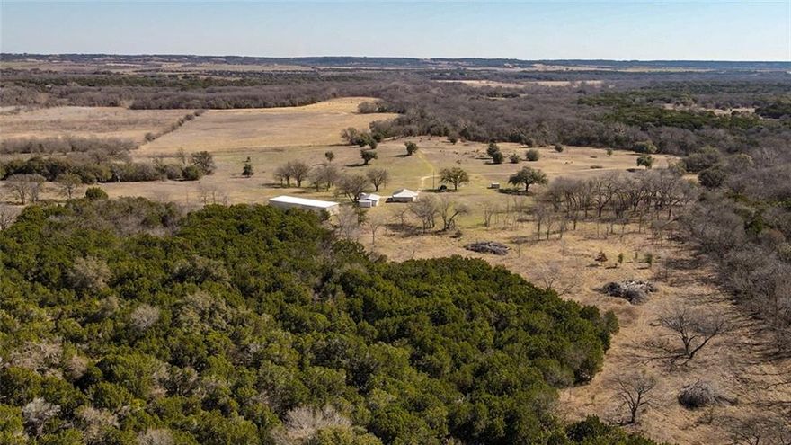 This stunning 181-acre ranch in Bosque County offers a perfect mix of open pastures, dense woods, and over 1,800 feet of North Bosque River frontage. Located just off Highway 6 in Meridian, the property features a spring-fed creek, rolling terrain, and abundant wildlife, making it ideal for ranching, hunting, or recreation. Improvements include a beautifully remodeled 1957 rock home, multiple barns, storage buildings, and a garage. With two water wells, a productive coastal pasture, and breathtaking views, this ranch is a rare find. Utilities include United Cooperative and Cell Hotspot, and a portion of the mineral estate is negotiable. Whether you’re looking for a peaceful getaway or a working ranch, this property has it all. As you enter the ranch, you’ll cross over the picturesque Gibson Branch Creek before reaching 
the expansive open pasture on the northeast side, which is covered in improved grasses. This 34-acre coastal pasture is highly productive, typically yielding two to three cuttings of hay per year. Moving further into the property, the terrain becomes more rugged and heavily wooded with 
large oaks, mesquites, and cedars, creating a prime habitat for deer, turkey, and other wildlife. The diverse topography includes natural trails, varied elevations, and scenic views, making it perfect for outdoor enthusiasts, hunters, or those seeking a peaceful escape. The rock ranch house provides both comfort and practicality. The residence is a charming rock home, originally built in 1957 and completely remodeled in 2017, has been modernized with new electrical, plumbing, heating and cooling systems, and spray foam insulation for energy efficiency. The renovation also included high-end granite countertops, stainless steel appliances, new flooring, double-pane windows, and updated blinds and doors, blending modern convenience with classic ranch-style living. Supporting the ranch’s operations are several well-maintained structures. A red hay barn, located 
on 12