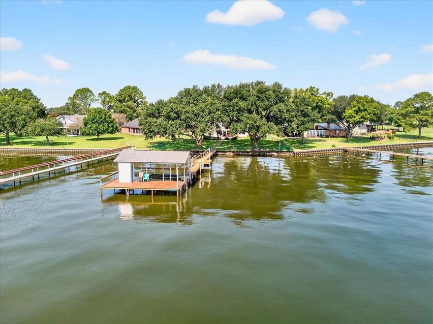 Discover this stunning waterfront home on Cedar Creek Lake! Enjoy the lake life at its finest with this beautiful 4-bedroom, 4-bath home with 112 ft. of open water in the family loving Key Ranch Subdivision. Wake up to breathtaking sunrise views and huge mature trees in your fenced and landscaped backyard while sitting and enjoying your coffee under your covered porch with a fireplace. Direct water access to your private boat house with boat slip and jet ski lift. The spacious interior features an open floor plan, a wall of windows, hardwood floors, granite countertops and WBFP. Don’t miss the opportunity for your family to own this piece of paradise! Buyers and buyers agents are responsible for confirming all information provided. Survey and T-47 provided. Furnish package available.