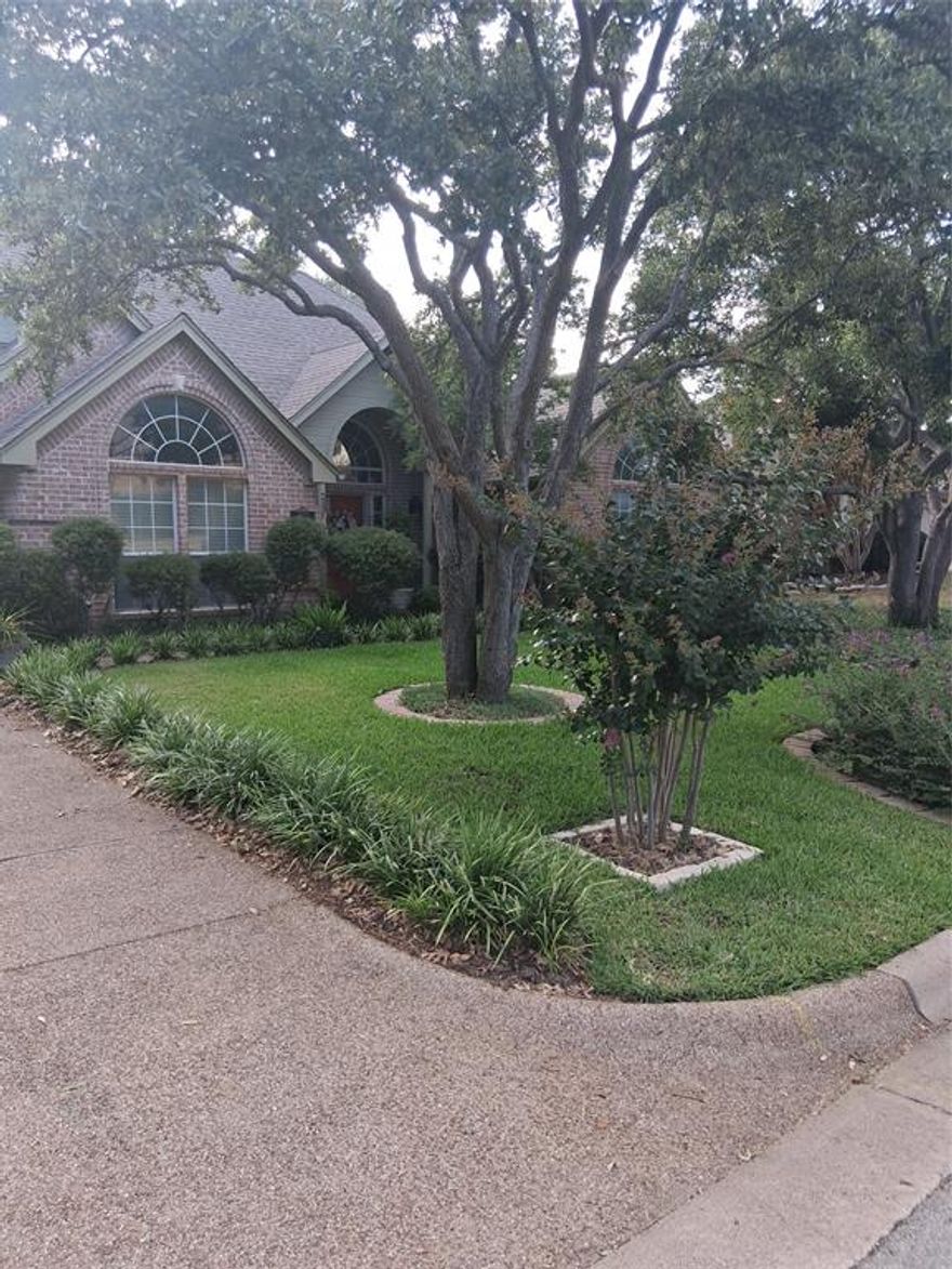 Traditional brick single family dwelling. Manicured front yard with ivy, trees and lawn
