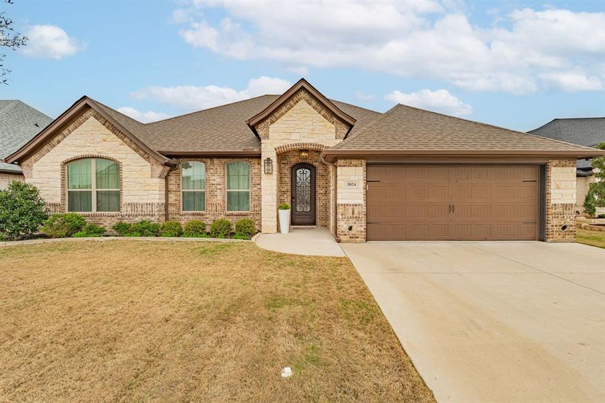 Located in the sought-after Harbor Lakes community in Granbury, this 2021 Couto-built home reflects quality construction and thoughtful design throughout. The open layout centers around a spacious kitchen with granite countertops, gas cooktop, and a large island overlooking the living area. A stone fireplace anchors the room, while tray ceilings with detailed crown moulding add architectural depth without overpowering the space. Wood-look tile flooring runs through the main living areas, offering the warmth of hardwood with durability and easy maintenance.
The primary suite includes an ensuite bath with garden tub, separate shower, dual vanities, and a walk-in closet. The floor plan flows comfortably from room to room, balancing everyday function with refined finishes.
Out back, a covered patio extends the living space outdoors — ideal for hosting friends, grilling on the weekends, or enjoying a quiet evening at home.
Harbor Lakes is centered around the Harbor Lakes Golf Club and is just minutes from Lake Granbury and the historic Granbury Square. The neighborhood offers convenient access to golf, the lake, dining, and local shops while maintaining a quiet, established setting.