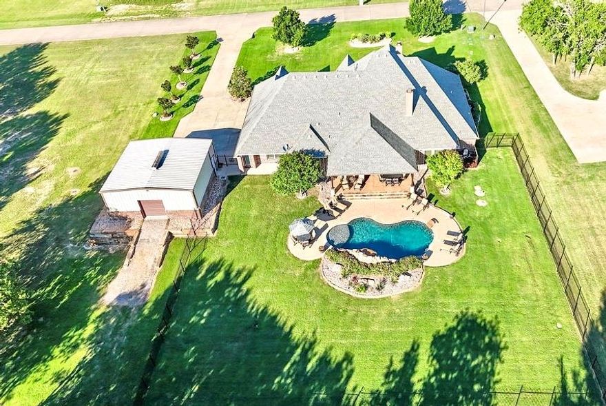 Welcome to 1387 Shadow Lakes Drive a true masterpiece of Old-World Charm and modern luxury set on 1.23 lush tree filled acres. This 4-bedroom, 3.5 bath estate features formal dining, a private office, game room and an oversized garage offering comfort and functionality at every turn. Step outside to your personal custom pool with waterfall, built in BBQ and cooktop, outdoor fireplace with TV, and over 1600 sq ft of covered patio space all framed by mature landscaping, led lighting, and a custom iron fence. This property also has a fenced in raised garden with multiple fruit trees that backs up to a green belt so you can enjoy the beautiful views while also maintaining privacy. Inside enjoy soaring 12 ft ceilings, 8 ft solid core doors, multilevel crown molding, custom plantation shutters throughout. A full mother n law suite with a private entrance and walk in shower adds flexibility, while the gourmet kitchen boasts dual ovens, gas LPG cooktop, dual 1200 CFM fan, soft pellet ice machine, and both a walk in and butler's pantry. Additional upgrades include custom storm shelter, epoxy garage floor, engineered attic space with stair access and a 30 x 30 insulated shop encased in a natural stone retaining walls. With every feature thoughtfully designed for luxury and longevity, this home offers an unparalleled living experience.