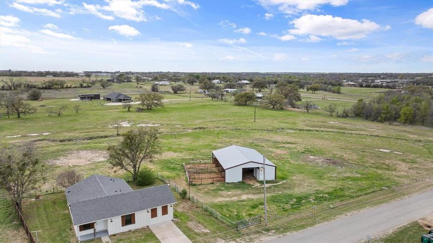 Completely updated from top to bottom, this charming three-bedroom, two full bath, modern farmhouse blends cozy country living with high-end finishes. Featuring full insulation, brand new windows, gutters, wood exterior shutters and custom trim with every detail impeccably done. Inside, you’ll love the warm, light pecan-toned luxury laminate flooring, thoughtfully designed decorative touches like decorative lighting, new appliances, stylish shiplap feature walls, and sliding barn doors that add the perfect rustic charm. The spacious open floorplan includes a full laundry mudroom, and generously sized closets throughout. Step outside to 6.25 beautiful acres, fully equipped for horse lovers. The property includes a 40x55 barn with four stalls and 12x20 runs, a tack room, and large runs that open to an open pasture, ideal for riding or turnout. Conveniently located within walking distance to the school and just minutes from town, this property offers the perfect balance of peaceful living and accessibility. This one has the modern updates, country charm, and space to spread out. This property is in the City Limits, some restrictions apply.