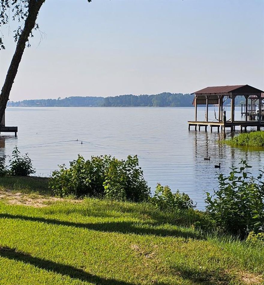 Quaint waterfront custom built home with split bedroom plan, large kitchen with attached dining room area; DR is open to the living room which has a WBFP, built-in cabinetry and lake views. Master BR has built-ins, a view of the lake, and en-suite bathroom. Nice lake view from the expansive rear porch.  Cape Tranquility has a waterfront community park with pavillion, which may be leased by residents for gatherings, a boat ramp, two docks. Roads repaved 2 or 3 years ago. Two large utility closets off of the two-car carport, with additional parking beside the driveway.  Irrigation via lake pump.  Upper Neches leased land that goes with the home is approximately 80' x 230' or just under a half-acre, as shown on Survey; the lease for Upper Neches land plus irrigation pump is about $100 per yr.