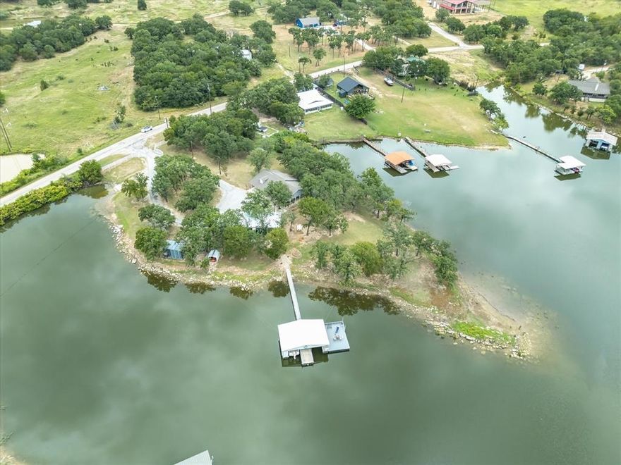 Discover unmatched privacy and sweeping water views with this incredible Lake Bridgeport retreat. Situated on its own point with no neighboring properties touching it, this home offers the perfect blend of seclusion and lake life convenience. The main home features a little over 2,000 sq. ft. with 2 bedrooms, 1 bathroom, and an open floor plan designed for gathering and entertaining. Spacious living and dining areas flow into a kitchen that overlooks the lake, complete with electric appliances and a large pantry. Every window offers a water view, while ceiling fans, walk-in closets, and abundant natural light add comfort throughout. Step outside to the back porch and deck to relax and take in the panoramic scenery. Guests will love the separate bunkhouse at 514 square feet, outfitted with LVP flooring, a counter prep area, built in cabinets and a mini-fridge. Full bathroom with shower, stackable washer and dryer, and plenty of space to unwind. Between the bunkhouse and the two-car carport, you’ll find a storage building for extra gear for the lake or make it small a workshop. Your private boat dock comes with two slips each 8'x22', a spacious 16'x25' deck for watching the action on the lake, and electric stairs that lead directly into the water. Makes getting in and out of the water a cinch. A private boat ramp makes launching easy, while a full walk-in cooler for cleaning and storing fish. There is a  2,500-gallon water tank with hydrogen peroxide treatment system. This fenced property with a gated entrance add even more convenience and security. With central AC only 1.5 years old, ample parking, and multiple covered seating areas, this property is ready for you to start enjoying the peaceful lake life today. Get with your agent on showing times! Whether you are looking for an investment property, a vacation home or live the lake life every day; Don't miss the opportunity to see this unique lake front property! Book your showing today!