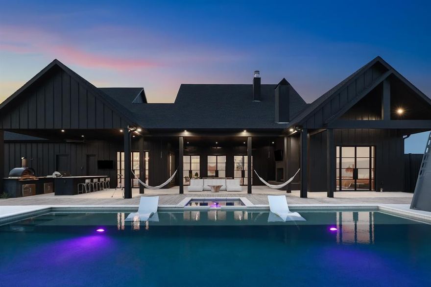 Welcome to VERAI, bold and breathtaking fusion of modern luxury and ranch style autonomy, set on 69 expansive, cross fenced acres just 25 minutes from the city. Designed as a fully self-sufficient smart estate, this is more than a home, it’s a destination for those who desire elegance, privacy, and the freedom to expand. Step through the grand entry into an atmosphere of clean lines and curated design. The main residence offers 5 full bedrooms, 7 luxurious bathrooms, plus a private guest house, all controlled effortlessly through Control4 smart home technology, including sound, lighting, and security. Anchored by a sleek chef’s kitchen, custom dry bar, wet bar, and a dramatic gas fireplace, the interior exudes warmth and modernity. Every space is crafted for both intimate living and grand scale entertaining, with soaring ceilings and seamless flow into multiple living areas, offices, and formal spaces. The primary suite is a true sanctuary, featuring dual spa style bathrooms and two expansive walk-in closets. Each additional bedroom is en suite, offering comfort and privacy for guests or family alike. A private resort, heated pool and spa, putting green, outdoor kitchen, multiple ponds, and luxury lounging spaces beckon under open Texas skies. The property includes a generator, four wells, a full barn with attached pens, and is already equipped with cross fencing for livestock or equestrian use. With room to build additional residences, VERAI is ready to become a multi-generational compound or a curated retreat estate. Whether you seek bold adventure, quiet retreat, or legacy living this is your canvas.