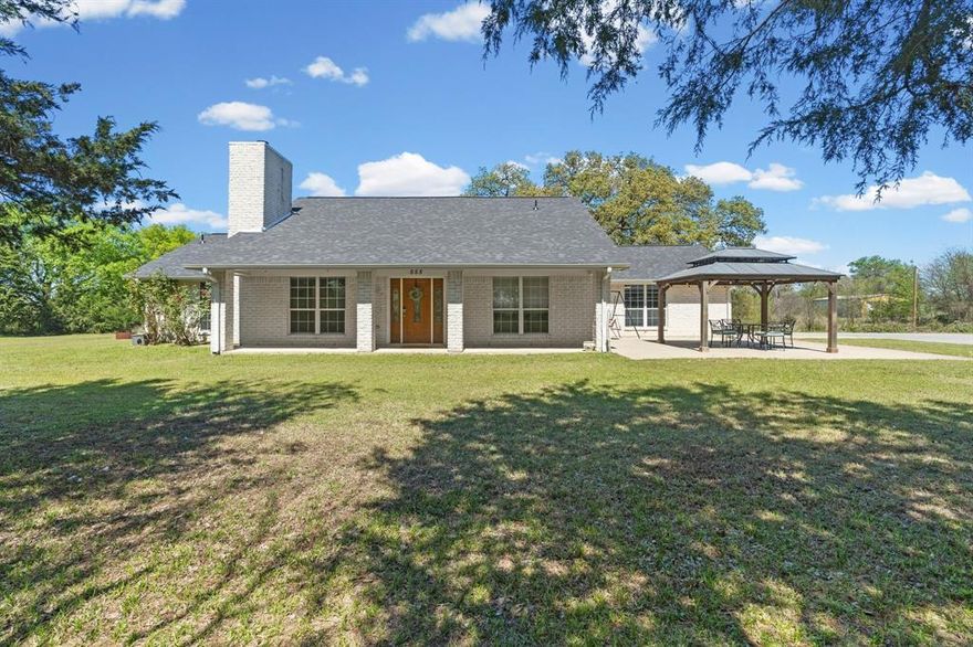 The kind of place where you actually notice the stars again. Enjoy a quiet, gently wooded setting on nearly an acre, with a strong sense of privacy and open East Texas skies. This 3 bedroom, 2 bath brick home offers a comfortable split bedroom layout that gives the main suite extra separation, along with an easy, open flow between the kitchen and living area. The kitchen includes an island and breakfast bar, and opens to the living room, where the fireplace creates the perfect gathering spot. Ceramic tile and other solid-surface flooring in the main areas help keep everyday living simple and low maintenance, and a new roof installed in the summer of 2025 adds peace of mind for years to come.
The generous main bedroom feels spacious enough for a sitting area or extra furniture, giving you room to spread out. Step outside to a fenced backyard and a charming gazebo that’s ready for quiet mornings, evening unwind time, or casual get-togethers. There is plenty of space for a future shop along with parking for boats, RVs, and other gear. On city sewer yet surrounded by a distinct country feel, this Rains County home sits within easy reach of Emory and Greenville, delivering that East Texas dream of room to breathe without giving up convenience.