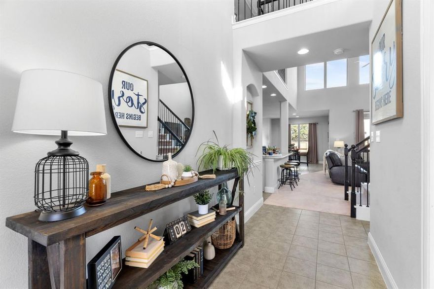OPEN HOUSE SATURDAY, MAY 9, 12-2PM! Meticulously maintained two-story brick home with an extended front porch, ideally located in the desirable Trinity Falls community of North McKinney. The striking exterior features black shutters, a herringbone brick detail above the two-car garage, and an elegant front door with frosted glass, wrought iron accents, and keyless entry. Inside, the dramatic front entry impresses with soaring 19-foot ceilings, a chandelier, and a stunning wrought iron staircase leading to a suspended bridge overhead. A private office behind glass-pane French doors offers flexibility as a fourth bedroom. The living room feels both grand and inviting with towering windows, plush carpet, and a gas fireplace with mosaic tile and white mantel. The chef’s kitchen features pristine white cabinetry, soft gray granite countertops, white subway tile backsplash, an oversized island with bar seating, and a large French-door pantry. Whirlpool stainless steel appliances include a built-in oven, gas cooktop, microwave, and dishwasher. The dining area offers backyard views and direct patio access. The first-floor primary suite includes plush carpet, a tray ceiling with fan, and French-door access to the spa-like bath featuring a walnut dual vanity with quartz counters, tiled shower with bench, private water closet, and a spacious walk-in closet with built-ins. The second floor loft could serve as a game room or second office, and the private media room is the perfect space for watching movies or the big game. Two secondary bedrooms and a full bath can also be found upstairs. Entertain guests in the oversized backyard with covered patio, ceiling fan, gas grill stub, wood fence, and open green space. Trinity Falls residents are spoiled with resort-style pools and splashpads, trails, dog and frisbee parks, and an onsite elementary school with quick access to Hwy 75, H-E-B, Buc-ee’s, and McKinney shopping and dining.