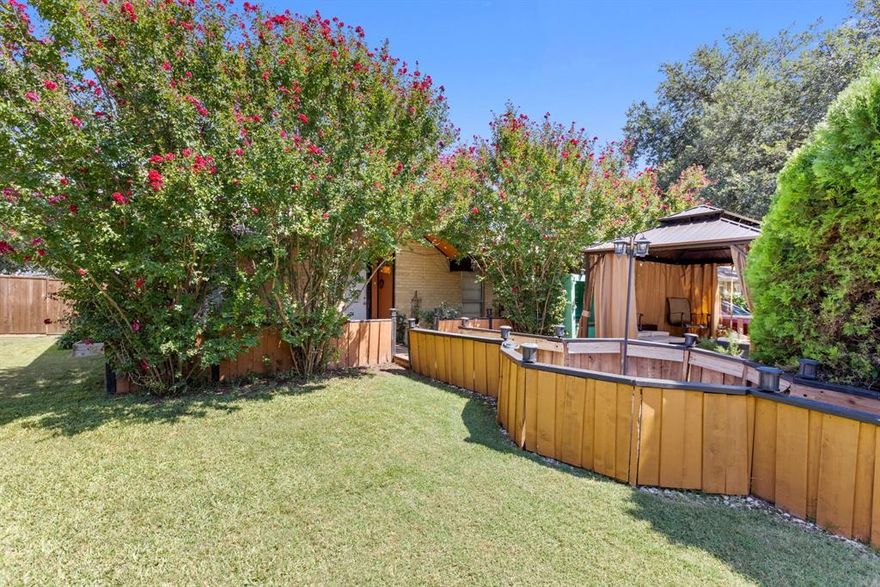 This one-of-a-kind, single-story Plano residence is bursting with personality and eclectic character. Ideally situated in the heart of the DFW Metroplex, you're invited to explore the many distinctive features this home has to offer, both inside and out. From the street, massive evergreen shrubs conceal the front of the home, providing the utmost privacy and seclusion. Experience a unique entrance as a wooden walkway guides you through a canopy of mature crape myrtle trees to the front door. The curtained gazebo is perfect for sipping your morning coffee or simply enjoying the serene outdoors. Leave the ordinary behind and step inside to discover a kaleidoscope of color and bold designs. Upon entry, the spacious living area features a dry bar, making entertaining a breeze. Just off the kitchen, a dedicated media room serves as an ideal spot for family movie nights or game day gatherings. With three bedrooms, two full baths, and an abundance of versatile living spaces, there’s plenty of room for the whole family. Let your imagination run free and transform each space to perfectly suit your lifestyle. The backyard offers a mix of enclosed and open spaces, making it adaptable for a variety of uses. Incredible location provides quick and convenient access to 75, along with endless shopping, dining, and entertainment options nearby.