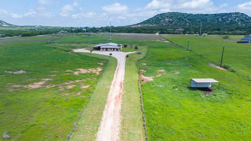 Located just outside Ovalo, TX, this 2013 barndominium on ~21.26 acres at CR 162 & 382 offers a blend of rustic charm and modern living. The open concept home features 3 beds, 2 baths, and an office or storage room. Enjoy outdoor living on the expansive covered front and back porches, the latter boasting a stone fireplace. A gravel drive and carport provide ample parking.

The property consists of fenced native pasture with level to sloping topography, typical for the area. Utilities include rural water and a septic system. Inside, find tile floors in the main areas and carpeted bedrooms. The entryway features shiplap walls and built-in storage. The kitchen is well-equipped with white cabinets, stainless appliances, and an island with seating. The dining area is spacious, and sliding barn doors offer flexible space. The primary bedroom includes convenient washer-dryer hookups.

Property details include Taylor County Appraisal District ID 982882. Previous year's ag-exempt taxes were $3743. Wildlife typical for the area includes deer, varmints, dove, among others. A highline utility easement crosses the property. No mineral rights are included. Access is via blacktop county roads CR 162 and CR 382. GPS: 32.159443838848645, -99.80443906375935.