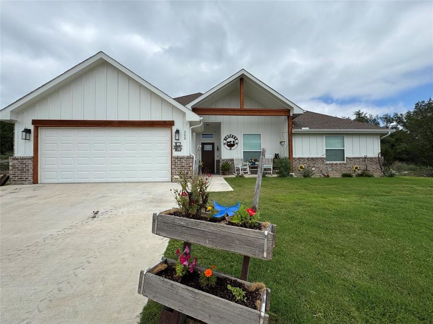 Nearly new, 3-bedroom, 2-bath home with a 2-car garage, perfectly situated on a scenic 1-acre lot. Enjoy stunning sunsets from your hilltop front porch view and take in the peaceful surroundings of the sought-after Mountain Lakes Ranch community. Step inside to find upgraded finishes throughout, including custom cabinetry, quartz countertops, and luxury vinyl plank flooring in the main living areas and primary suite. Tile in wet areas adds durability.   The open-concept kitchen is a dream for any home chef—featuring a breakfast bar, double ovens, built-in microwave, generous pantry, and plenty of space for both cooking and casual dining. The spacious living room is ideal for entertaining or relaxing, complete with a charming brick wood-burning fireplace and large windows that frame serene backyard views. An 11-foot boxed ceiling adds elegance and a sense of openness. The split-bedroom layout offers privacy, with a luxurious primary suite that includes a soaking garden tub, oversized walk-in shower, dual vanities, and two large walk-in closets. Guest bedrooms are generously sized and share a stylish full bath with a tub-shower combo.  Enjoy access to two private lakes, a swimming pool, RV parking and storage, fitness park, playground, and more. Plenty of elbow room, lots of wildlife; you will enjoy the hill country that Mountain Lakes Ranch offers.