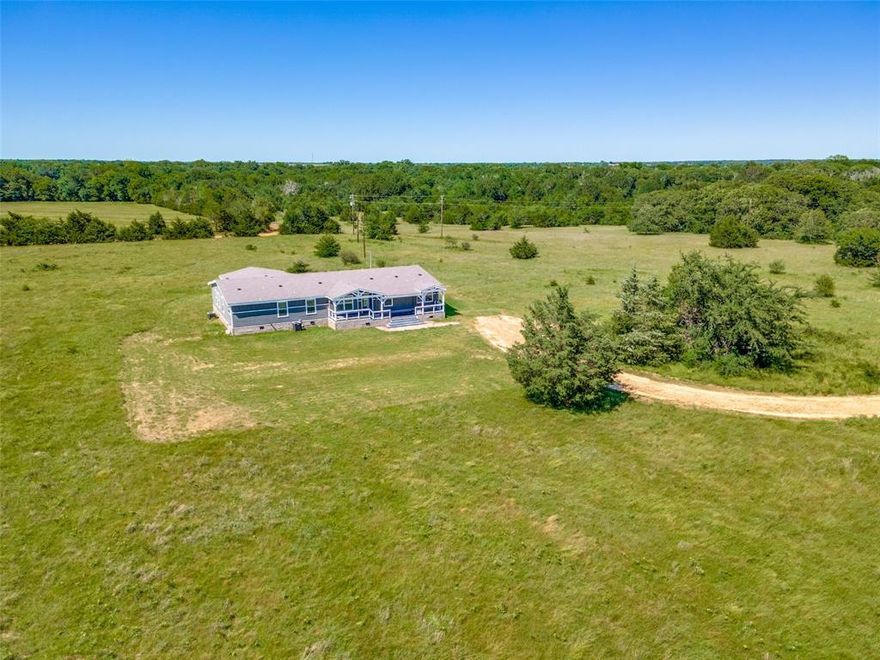 Discover your dream escape on this expansive 18-acre property. This stunning 2022 4-bedroom, 3 bathroom home features an office, a bonus room, and a game room, perfect for work-life balance and family fun. The 3006 Sq ft TRIPLE wide design offers ample space and flow, making it ideal for entertaining and everyday living. The great room encompasses a breakfast nook, breakfast bar, and a formal dining area. Kitchen highlights subway tile backsplash, stainless steel farm sink, elegant lighting, and faux granite counter tops. The extra-large primary bedroom features a sitting area and large windows accented with beautiful outdoor views. The en-suite bathroom boasts a garden tub with gorgeous dark tile surround, a tile shower, and modern bowl sinks. Imagine relaxing in the spacious great room, working from home in the dedicated office, or enjoying the tranquility of your private oasis amid 18 acres of gorgeous green pasture on one of two covered porches. Property is partially fenced and perfect for your ranch or farm animals. Privacy and seclusion enhance the stunning home that is ideal for raising a family, entertaining or just relaxing. The bonus room has it's own covered porch entrance, making it perfect for guests. Too many features to list.  You won't believe this one until you see it!