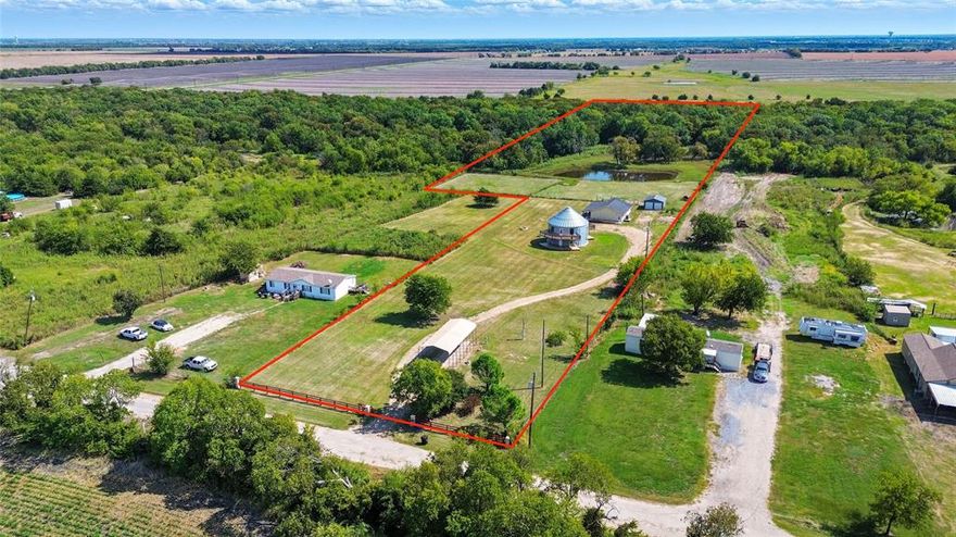 Looking for something truly special? This extraordinary property sits on 8.4 acres with a private pond and offers not one, but two distinct homes, a rare find brimming with character and endless possibilities! The main residence is a charming one-story featuring 3 generously sized bedrooms (one perfect for a home office), gleaming hardwood floors, and an inviting layout with a spacious living area and stacked dining room. The kitchen boasts built-ins, an electric cooktop, and plenty of storage, while the updated bathroom offers dual sinks and a convenient laundry area. Enjoy evenings on the Texas-sized front porch, perfect for rocking chairs and sunset views. With no carpet, oversized bedrooms, and move-in readiness, this home is ideal for everyday living. But the magic doesn’t stop there, this property also includes a second home built from a silo, a true showstopper that blends rustic charm with modern comfort. Inside, you’ll find a farmhouse-inspired kitchen opening to a spacious living room, a large utility room, and a private suite with dual sinks, a walk-in shower, and a bonus flex space for a second living area, game room, or office. Outdoors, a wrap around patio areas create the perfect spaces to entertain, relax, and soak in the peaceful country setting. The land itself is a dream, fenced acreage dotted with mature trees, a tranquil pond, and plenty of open space for recreation, livestock, or future additions. Added perks include a 6-person tornado shelter, two septic systems, RV hookups with awning, and more room for a workshop, pool, sports court, or even another home. This is more than just a property, it’s a lifestyle. Whether you’re looking for multi-generational living, a unique income-producing setup, or your own private retreat, this one-of-a-kind gem delivers it all.