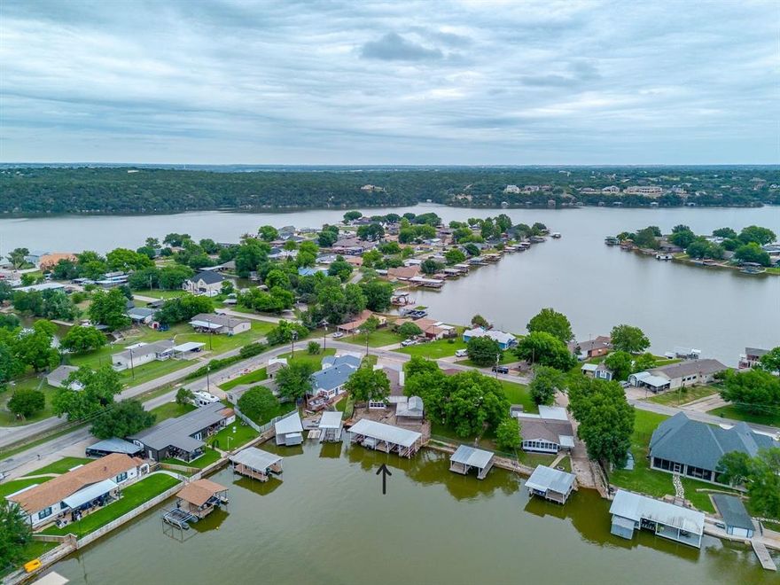 Experience the quiet luxury of waterfront living  on this rare lakefront retreat offering expansive outdoor living, exceptional dock infrastructure, and a lifestyle defined by peace, recreation, and unforgettable sunsets on the water. Perfectly positioned along the lake, this thoughtfully expanded residence—originally a manufactured home enhanced with multiple additions—has been transformed into a spacious and functional lake retreat designed to embrace indoor-outdoor living. A sun-filled sunroom invites natural light and serene water views, creating a seamless connection to the surrounding landscape. The true centerpiece of the property is the impressive covered wraparound metal dock, offering an extraordinary waterfront experience. Spanning approximately 52 feet by 30 feet, the dock is equipped for elevated lake living with two boat lifts, a double jet ski lift, and a single jet ski lift. Additional features include a dedicated fishing area, bait house-storage, and a bait system, all supported by dual remote lift controls for effortless access to the water. Designed for both relaxation and entertainment, the outdoor setting continues with a 12x24 workshop, additional storage structure with a covered wraparound deck, tool shed, and double carport. A stone walkway gracefully connects the home to outdoor living spaces, while a thoughtfully constructed retaining wall creates an inviting, elevated seating area overlooking the water. The natural rock shoreline presents additional opportunity for enhancement, with potential for custom plant ledges or expanded walkways that further elevate the waterfront experience and personalize the landscape. Whether envisioned as a private lake escape, a recreational retreat, or a high-potential short-term rental investment, this property offers unmatched versatility in a serene waterfront setting. The possibility of including a  Deck Boat further enhances its appeal for the ultimate lake lifestyle experience.