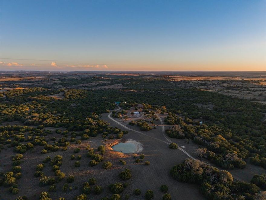 It is rare to find a ranch in this part of Lampasas County that feels this complete. This approximately 150 acre property sits in the heart of proven ranch country, minutes from Lampasas and within an easy drive of both Austin and Waco. The entrance off Highway 183 winds through native grasses, mature oaks, and pockets of cedar before revealing the ranch house and shop placed naturally within the landscape. The current owners cared for the land with intention. They were outdoors-people who understood how to manage a ranch without disturbing its integrity, and it shows in the quality of the habitat. Wildlife is abundant, with whitetail deer, turkey, dove, and a strong native bird population. Native American artifacts have also been found here, a reminder of the land’s long history. The home sits on a hill with views across the creek valley and much of the ranch. It has the warmth of a classic log style home with a traditional two story layout, vaulted living room, and wood interiors that create a timeless ranch feel. The second story porch looks out over the land, and the semi wrap around porch offers a quiet place to enjoy morning coffee or an evening drink. The home includes three bedrooms, two and a half bathrooms, and plenty of storage. The shop is tucked behind trees to keep the landscape undisturbed. It features covered parking, an extended overhang for dry storage, two roll up doors with a true pull through layout, and a lofted storage area. The land is the highlight. Elevation changes are noticeable the moment you drive the interior roads. Hardwoods, meadows, creeks, and ponds create a diverse setting that feels larger than the acreage. A signature high point offers a full 360 degree view toward Lampasas and captures the best of this region. This is a turnkey ranch cared for with pride and ready for someone who wants a classic Texas retreat close to major cities.