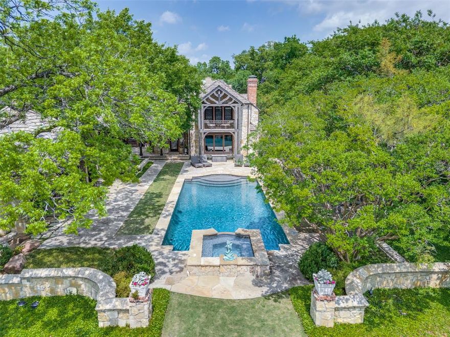 Welcome to 5106 Deloache, a Charles Dilbeck masterpiece! Dilbeck's careful approach to design resulted in warm and inviting homes. This beauty exemplifies his eclectic and visionary style. Upon arrival you are greeted by a gorgeous stone wall and custom-made security gate where this French Norman home presents itself. You will be overwhelmed by the stunning cathedral ceilings, rough-hewn log beams, gorgeous paneling, incredible oversized fireplaces, stained glass windows and all the nooks and crannies a Charles Dilbeck designed home offers. The property is as captivating as the home. This beautiful lot is 1.6 acres is canopied by abundance of trees, a koi pond, running river, cathedral like cabana with a massive fireplace, inviting pool, sport-pickle ball court, play yard, fire pit, gorgeous stone paved porches and bridges. The quarters above the oversized 3 car garage are an additional 1278 sqft, can be a great game room-office and guest house. Truly one-of-a-kind home sitting on the most beautiful lot. Don't miss this opportunity to own one of the few true architecturally significant homes in Dallas