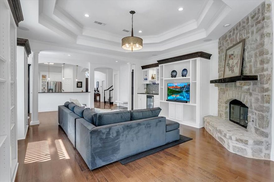 IN A CLASS OF ITS OWN! This custom K. Hovnanian home is perfectly positioned at the end of a quiet cul-de-sac, backing to a scenic greenbelt with an ideal east-southeast view. Designed with comfort and elegance in mind, this home offers a rare guest or in-laws suite with a private entrance—ideal for extended family, guests, or in home care provider. The exterior is beautifully landscaped with a wraparound patio, and arbor creating a peaceful setting perfect for relaxing or entertaining. Step inside to find rich wood floors, detailed crown molding, and large picture windows that bring in natural light. The home includes three fireplaces, 10’ and 11’ tray ceilings, built-in cabinets, granite countertops throughout, and a stylish wet bar with wine cooler—perfect for entertaining. The gourmet gas kitchen is equipped with a Bosch cooktop, stainless steel appliances, granite counters, a walk-in pantry, breakfast bar, and smart storage features like double pull-out shelves. The primary suite is a private retreat, complete with a cozy sitting room or office, a double-sided fireplace, and a spa-inspired bath featuring a custom walk-in shower. The oversized seasonal walk-in closet includes built-in shelves, soft-close drawers, and direct access to the laundry. The private guest suite has its own front door, living space, bedroom with built-ins, step-in shower, and a sit-down vanity—perfect for visitors or multi-generational living. Upstairs, you’ll find a large library with built-in bookcases, fireplace, projector and screen for movie night, and an additional bedroom and full bathroom, plus attic access for storage. This home is thoughtfully designed and full of luxury features—a must-see to fully appreciate!