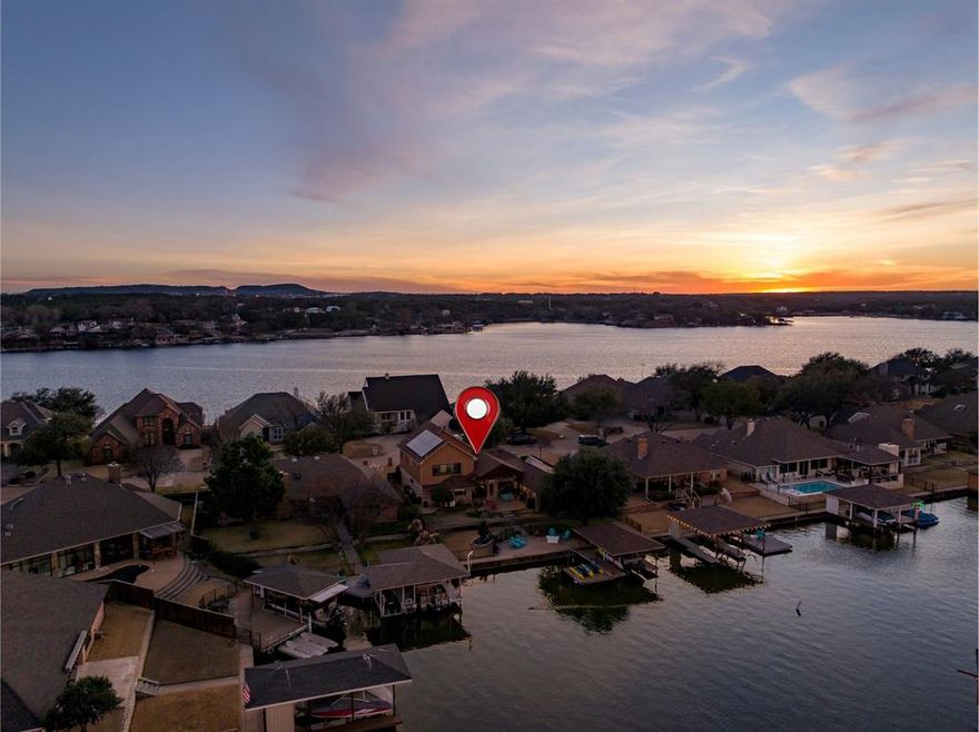 For a limited time, seller will include the boat with an acceptable offer before May 8th —offering a true turnkey lakefront lifestyle.

Beautifully remodeled lakefront residence located in Granbury’s sought-after Waters Edge. This home has been thoughtfully redesigned and captures the essence of refined lakefront living. A rare canal-corner setting provides long, open water views and added privacy, with no rear dock to interrupt the scenery. The property offers approximately 75 feet of wide, navigable, deep water frontage that flows out to the lake.
The kitchen is ideal for entertaining and everyday living, offering rare Patagonia granite countertops, upgraded appliances, a dedicated coffee bar, and a spacious butler’s pantry with room for two full-size refrigerators or freezers. The pantry leads to a discreet safe room with cabinetry that may also serve as additional pantry space.
The private primary suite features a walk-in closet, dual vanities, and a spa-style multi-head shower. A 2023 remodel nearly doubled the home’s square footage, adding two bedrooms, a full bath, and a bonus room suitable for a media room, office, or guest space. Energy-efficient upgrades include an encapsulated roof, solar-powered mini-splits, and two commercial-grade Trane HVAC units. Outdoor amenities include a covered patio, fenced backyard, sun deck, private covered dock with boat lift and lake pump irrigation.
If you are a golfer, Harbor Lakes Country Club is a short golf-cart ride away and offers both golf and social memberships. Conveniently located near town, you’re just a car or boat ride from restaurants, shopping and more!

HOA maintains greenspace and seawalls. 
All information is deemed reliable but not guaranteed. Buyer to verify all information.