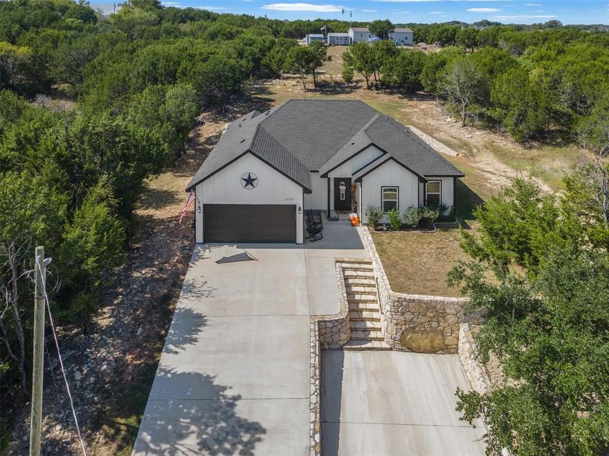 Perched on a hill surrounded by tranquil scenery, this 2022-built energy-efficient home perfectly blends modern comfort with peaceful living. The charming board-and-batten exterior welcomes you into a light-filled, open-concept layout ideal for both everyday living and entertaining. High ceilings, wide baseboards, and quality finishes create an inviting, upscale feel throughout. The kitchen is a chef’s delight with granite countertops, a center island with breakfast bar seating, walk-in pantry, and abundant cabinetry for storage. The open dining and living areas provide plenty of space for gatherings and relaxation. The spacious primary suite offers a spa-like ensuite complete with dual sinks, a soaking tub, walk-in shower, and a LARGE closet with built-in's. Two additional large bedrooms and a full bath ensure comfort for family or guests. Outside, enjoy the serenity of nature and the space you need to do as you please.  With ample parking thanks to a two-car garage and dual driveways—this home is perfect for hosting. The community features a private boat dock & ramp for lake access and a park for recreation. Located just minutes from restaurants, shopping, healthcare, and The Historic Granbury Square, this home offers the perfect balance of tranquility and convenience! Come see it in person. Life happens here.