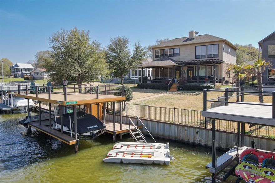 This fully furnished lakefront home is just off open water and boasts water views from 3 of the 4 bedrooms! 10 ft. ceilings, open living-kitchen with warm, rich wood tones and durable stained concrete floors. The downstairs primary bedroom-bathroom is thoughtfully laid out with large laundry connected to walkthrough closet. Spacious primary bath has tub, walk in shower and double vanity. There is a half bath downstairs for your guests. Upstairs you will find 3 more bedrooms and a Jack and Jill bath. One of these bedrooms is oversized and would make a great space for a bunk room. Covered patio for enjoying your time outside relaxing or entertaining by the lake. Dock with party deck has recently been redone with Trex decking for low maintenance enjoyment. Watch the sunset from the deck or take your boat-jet ski out for spin right out your back door.