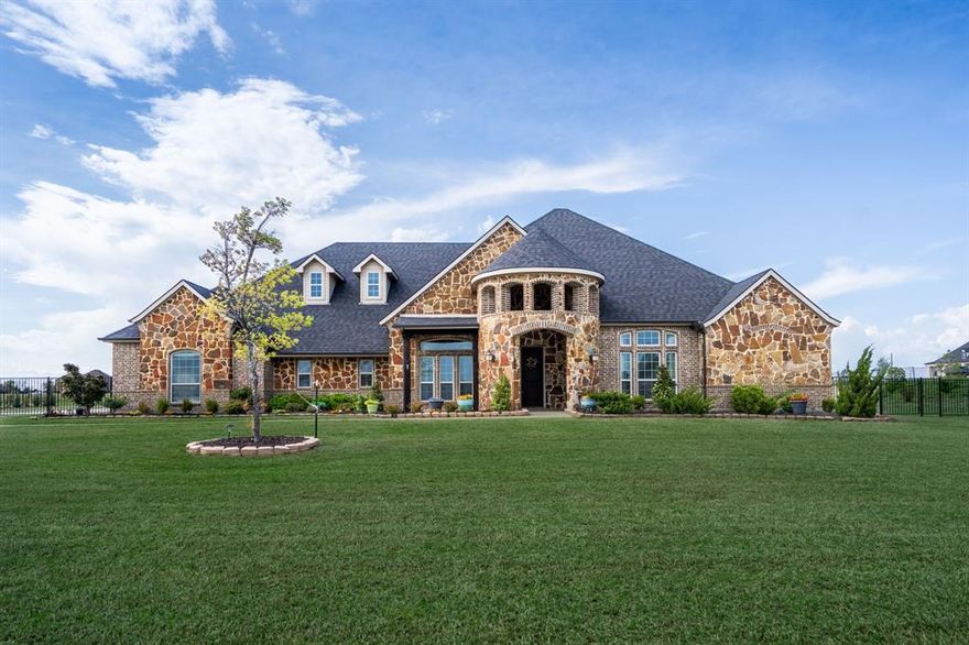 Exceptional design and refined finishes define this luxury single-story home on over 2 acres. A grand foyer with soaring ceilings, arches, & art niches sets a welcoming tone. The gorgeous kitchen features double ovens, 5-burner professional-grade gas cooktop, walk-in pantry, custom vent hood, & an oversized island and breakfast bar with seating for six. The spacious living area is anchored by a stone gas fireplace, lighted floating shelves, and a dramatic 5-ft chandelier. The private primary suite offers marble-look tile, tray ceiling, bay window, patio access, and a spa-style bath - Dual vanities, garden tub, walk-in shower with bench, & a large custom closet. Generous guest rooms, French-door study, & large game room provide flexibility. The climate-controlled sunroom (34x10) includes epoxy floors, cedar trim, solar screens, TV wiring, & more. Enjoy outdoor living under a pergola with fans & lighting, stone fire pit, and privacy landscaping. Gated driveway, turret-style porch, and 3-car garage complete the home.