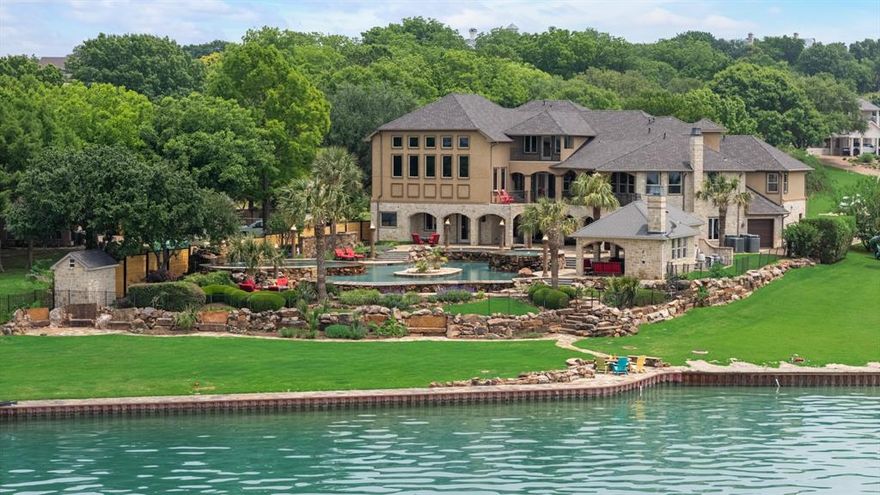 Experience the epitome of luxury waterfront living in this stunning LAKEFRONT ESTATE offering expansive lakeviews. The resort-style oasis features a blend of four distinct water experiences designed to create a relaxing paradise. At the heart is the infinity pool where the waters edge appears to spill into the lake. Alongside the infinity pool is an elevated hot tub, a wading pool with sloping entry and a diving pool with a rock waterfall, all complemented by multiple balconies and lounging areas ideal for sunbathing and relaxation. For the boating enthusiasts there is a boat dock with boat and sea-doo lifts. The chef’s kitchen is a culinary experience, featuring two islands, double microwave, undercounter wine fridge and ice maker, double refrigerator drawers, two Sub-Zero refrigerators, a Sub-Zero freezer, two dishwashers, and a Wolf double oven all designed for both everyday living and entertaining. Retreat to the luxurious primary suite, which includes a private living area, fireplace, custom closet system, and separate unique bathrooms with a sauna. The spacious guest suite offers a cozy fireplace, sitting area, and elevator, making it the ideal in-law suite. The entire 3rd floor is an expansive and versatile recreation area which includes a home theater, billiards, gaming, a lounging niche, and a kitchenette. Nestled within rugged stone walls, this sophisticated bar is a blend of rustic charm and modern luxury, a private retreat where craftsmanship meets connoisseurship. A Sub-Zero wine fridge is available perfectly preserving your collection of vintages at precise temperatures while a second Sub-Zero unit keeps glassware chilled. A built-in kegerator adds a touch of indulgence offering draught-quality beverages at the pull of a tap. The dual staircases and electric shades add convenience and sophistication to this exceptional estate. This property truly combines luxury, comfort, and functionality for the ultimate lakeside lifestyle. Owner financing available.