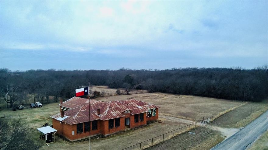 Designed by renowned Texas Architecture firm Voelcker & Dixon, the 7,000 square foot 1924 Spanish Fort High School is a testament to building practices that have stood the test of time. From its double brick walls, inch-thick plaster, vertical grain heartwood pine floors, this building is solid and ready for its next life. The fully fenced 2.6 acre property is nestled in the North Texas Hill Country and within thirty minutes Saint Jo, Nocona, three different wineries, and Red River Station concert venue. Several events throughout the year bring in thousands of tourists from across the region. With six classrooms ranging from 400-500 square feet and 2, 400 square foot auditorium and stage, this would make a great concert venue, wedding venue, boutique hotel or an additional winery as the property lies within the Texoma American Viticulture Area and soil samples have already been analyzed by Texas A&M. Underground 200 amp electric has been added with three 20 amp circuits and a small room and bathroom make it possible to stay overnight. Water is currently supplied by rain water catchment and high speed internet is active at the building. There is a well and septic but both systems should be considered in need of replacement. A copy of the original blueprints is available and will convey with the sale. Listing broker is the owner of the property.