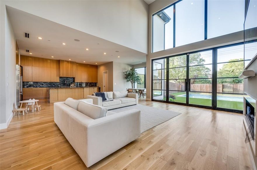 Modern architecture meets timeless elegance in this stunning custom home nestled in the heart of North Dallas. Designed for luxury and livability, this residence showcases soaring ceilings, clean lines, and expansive windows that fill the home with natural light. The open-concept living area features a dramatic two-story wall of glass overlooking the pool, a sleek linear fireplace, and seamless flow into the chef’s kitchen. The kitchen offers European-style cabinetry, a large marble waterfall island, high-end appliances, pot filler, and an impressive walk-in pantry. A stylish wet bar and formal dining room make entertaining effortless.

The first floor also includes a private office with fireplace, a spacious guest suite, and a family room that opens to the covered outdoor living area. Upstairs, the serene primary suite boasts vaulted ceilings, treetop views, and a spa-like bath with freestanding tub, dual vanities, and a large glass-enclosed shower. The boutique-style 2 story primary closet features custom cabinetry, abundant storage, and a statement chandelier. Three additional bedrooms each include walk-in closets and designer en-suite baths, with a versatile playroom or secondary living space completing the upper level.
The backyard retreat offers year-round enjoyment with a resort-style pool, synthetic turf lawn, and covered patio with fireplace and mounted TV—ideal for outdoor entertaining. Additional highlights include a media room, mudroom, designer lighting, wide-plank white oak flooring, and an oversized three-car garage with electric car charger.

This residence delivers exceptional craftsmanship, striking modern design, and a functional layout for today’s lifestyle—all within minutes of premier shopping, dining, and top Dallas schools.