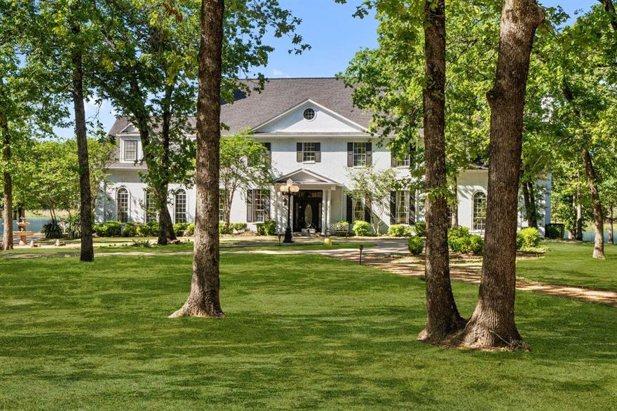 Leave the city behind and immerse yourself in unmatched luxury and seclusion on this extraordinary 50-acre estate. Enter through a gated entrance and follow a lamp-lit, paved driveway that winds through immaculate landscaping and towering trees. At the end of the drive, a stunning 4,780 sq. ft. custom-built manor surrounded by private lake, seamlessly blending classic elegance with cinematic grandeur. Step inside to discover rich hardwood floors, handcrafted finishes, and five stately fireplaces that create warmth and sophistication throughout. The dramatic foyer opens to a formal dining room, a spacious home office or secondary living, and a grand living area complete with a full wet bar—ideal for hosting guests in style. The gourmet kitchen is a chef’s dream, featuring travertine tile, a striking copper backsplash, granite countertops, a large island with a built-in cooktop, and a sunlit breakfast nook.The luxurious owner’s suite offers a peaceful retreat, with its own private sitting area, double-sided fireplace, three walk-in closets, an expansive en-suite bath with Jacuzzi tub and separate shower, and a private balcony with tranquil views. Outside, your personal resort awaits. Relax by the sparkling pool and spa, entertain at the outdoor bar and gazebo, or unwind by the firepit under the stars. Additional features include a 1,025 sq. ft. industrial-grade workshop with a climate-controlled 24x24 space and full bath, a chicken coop, greenhouse, two covered awnings, and miles of private nature trails to explore. A rare offering of timeless sophistication, natural beauty, and total privacy.