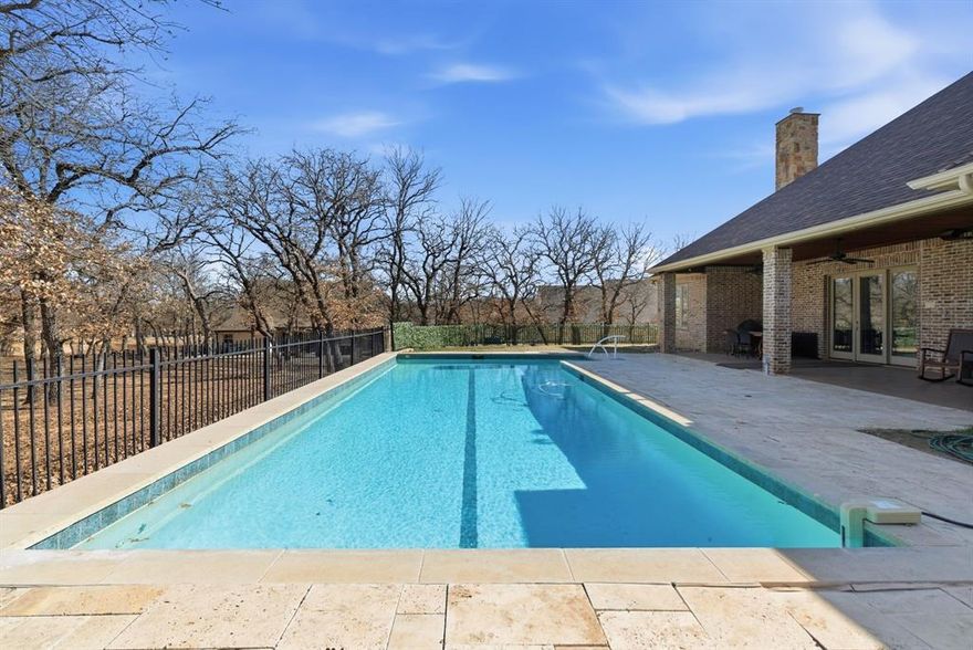 Poised beneath a canopy of mature trees on a gorgeous one-acre lot, this timeless Texas stone home offers a peaceful setting surrounded by natural beauty. Every detail reflects thoughtful craftsmanship, from hand-troweled walls & ceilings, custom crown molding & trim, arched windows & doorways, soaring ceilings, & solid 8-foot knotty alder doors. Natural light pours through Pella windows, drawing you into the impressive living room with 14-foot ceilings & a dramatic floor-to-ceiling stone fireplace. The kitchen is designed for those who love to cook & host, featuring beautiful custom knotty alder cabinetry, generous prep counterspace, a premium WOLF gas range, RO water system, & a walk-in pantry. A formal dining space & sunny breakfast area provide room for everything from holiday dinners to casual coffee mornings. The massive primary suite offers recessed ceilings, new carpet, & a spa-inspired ensuite with dual vanities, two walk-in closets, a jetted soaking tub, & a walk-in shower. Split secondary bedrooms. The versatile office or flex space adapts easily to your lifestyle. Step outside to the expansive covered back patio & take in views of the sparkling saltwater lap pool that sets the stage for long summer afternoons, evening swims, & relaxed weekends spent at home in your own oasis. Set within the gated Reserve at Sugartree, life here naturally extends beyond your front door. You can traverse the 18-hole Sugartree Golf Course tracing the Brazos River. Explore the clubhouse and pro shop for casual meals or a quick stop between rounds. Enjoy a community pool, fitness room, & pavilion for shared gatherings. Wildlife wanders peacefully through the neighborhood, adding to the sense of retreat & serenity. All of this is set within one of Parker County’s premier golf communities, in highly sought-after Brock ISD, & just 15 miles from Weatherford, close enough for convenience, yet far enough to feel like an escape.