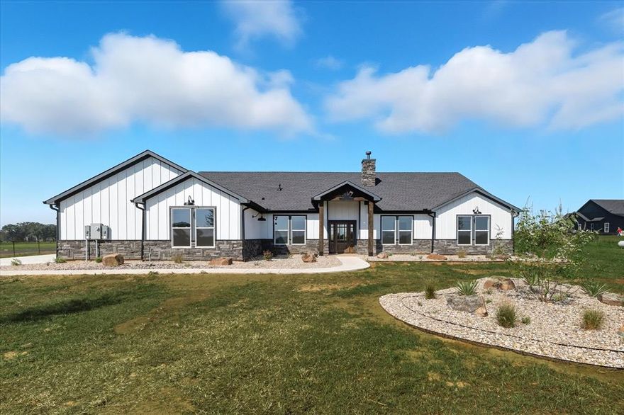 Situated on 4.88 acres of serene pasture land in the new Club Lake Ranch addition of Whitesboro, this custom built home blends southwestern style and modern finishes. Right of the foyer is a generously sized office with a breathtaking view of the rolling ranch across the street. Further inside, you are greeted by a comforting aesthetic and ideal layout, with an open concept kitchen and living area featuring natural wooden beams positioned on the vaulted ceiling, custom built ins and cabinetry with a richly stained finish, wood burning stove, large kitchen island with designer light fixtures, and a commercial grade, gas range. The expansive primary bedroom boasts a private oasis of a bathroom with a huge shower and elongated vanity featuring dual sinks and ample cabinet storage. On the opposite side of the home are the two guest suites, each with walk in closets, and a separate full bath offering a unique layout to allow for both privacy and functionality. The utility area close to the garage is fully equipped with a custom mud bench and storage, half bath, and oversized laundry room with plenty of space for additional cabinetry, hanging racks, or refrigerators. Out back is an exceptional covered porch overlooking the beautiful pasture with ample lighting and ceiling fans, making it an ideal entertainment spot, or for relaxing after a long day while watching the sunset in the west. The property is fully enclosed with pipe and no climb fencing, with cross fencing already installed for animals. Enjoy the convenience of being just a short drive to downtown Whitesboro, schools, or parks, all while embracing the feeling of being out in the country.