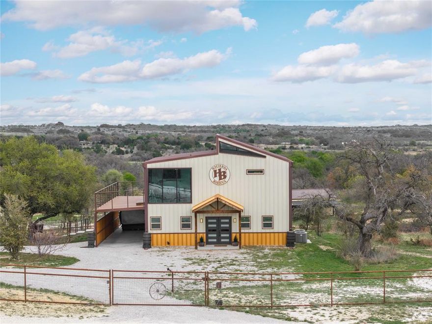 Welcome to this custom-built 2022 barndominium-style home in the gated Comanche Hills Subdivision, set on just over 10 acres with breathtaking panoramic views. Designed with a modern rustic industrial style, this exceptional property blends luxury living, outdoor recreation, & functional ranch amenities.

Inside, the home features luxury vinyl plank flooring & an open-concept layout ideal for entertaining. The spacious living area includes an electric fireplace & wine bar with built-in wine fridge & water dispenser. The kitchen offers granite countertops & bar seating, while the laundry room includes granite counters, sink, & a dog wash station. All appliances convey, along with 3 smart TVs & surround sound systems.

The primary suite is a private retreat with abundant natural light & a balcony showcasing incredible views. The en suite bath has a large tiled shower with LED color-changing lighting, double granite vanities, & 2 walk-in closets. An additional upstairs bedroom also enjoys stunning views, while the office features glass doors leading to the wrap-around balcony.

Outdoor living shines with a covered porch, complete with a spa & outdoor pool table for relaxing or entertaining. A fenced dog run adds convenience.

The property includes a 60' x 20' shop with 14-ft roll-up doors, a 30' x 16' shop or future guest quarters with electric & plumbing in place, & an RV carport with full hookups. Equestrian & livestock facilities include 4 - 12.5' x 20' stables with automatic waterers, fans, & covers, plus a 5th stable or hay room & enclosed tack room. Trails for dirt bikes, mountain bikes, or horses run through the property, along with a high-fenced garden area.

Private well with filtration & generator hookup, plus it is ag exemption for bees located at the back of the property.

This rare property offers luxury, privacy, incredible views, & ranch-ready functionality—must be seen in person to fully appreciate.

Relaxed POA to keep property values up.