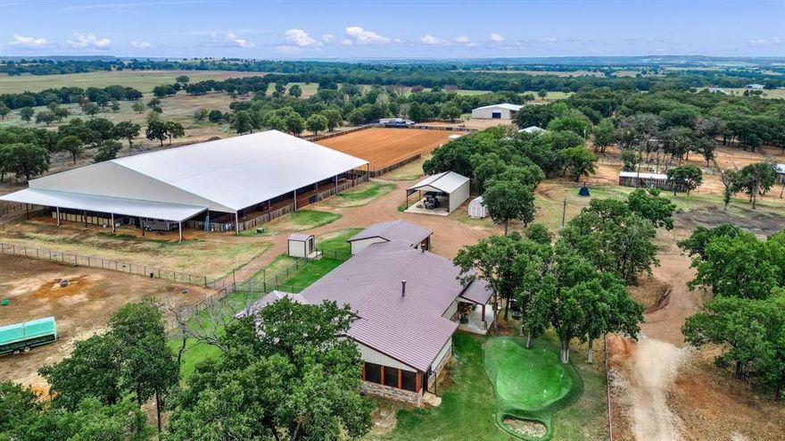 This impressive equine facility sprawls across 100 acres and features a spacious 4,051 SF 3-bdrm, 3-bath home on its own well. The property boasts a covered arena, an outdoor arena, a 16-stall MD barn, a hay barn, covered RV parking and a convenient 4-bdrm, 2-bath mobile home. The house itself is a masterpiece with vaulted ceilings, rock fireplaces and an open floor plan. The kitchen is a chef’s dream with granite countertops, stainless appliances, a substantial island, an adjacent pantry and a large mudroom. The primary bedroom is a retreat with French doors opening to a screened-in porch. The barn and mobile home share their own dedicated well. This property offers more than just stunning amenities; it includes lush coastal hay pastures dotted with majestic oak trees and 7 traps with loafing sheds and automatic waterers. A haven for horses! Its strategic location provides quick access to town and is perfectly situated for horse shows in DFW or OKC, or a night out at the casinos.