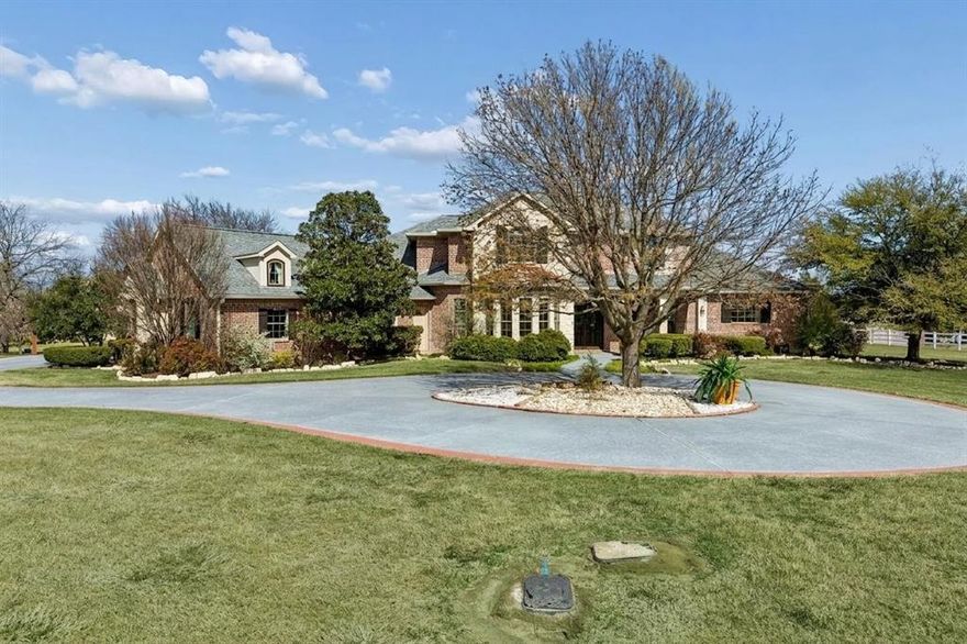 Welcome home to a masterfully crafted custom estate set on 2 quiet acres in the heart of Lucas and the top-rated Lovejoy ISD. A circular drive leads to a double front door entry, setting the tone for the warmth and quality found throughout this home. Inside, the thoughtfully designed floor plan opens to living spaces anchored by a large kitchen featuring a center island with prep sink, dual ovens, and generous counter space flowing into the family room for everyday living and entertaining. The primary suite offers a spacious ensuite bath with separate his-and-hers closets and large shower with multiple body sprayers designed for the most discerning buyer. A private guest bedroom on the main level provides a welcoming haven for visitors or MIL suite. Upstairs includes 2 additional bedrooms each with an ensuite bath, a game room with wet bar, an enclosed balcony overlooking the lush grounds and a dedicated media room. Step outside to discover a private backyard sanctuary designed for both grand entertaining and quiet escape. The centerpiece is a sparkling diving pool and separate hot tub, perfectly positioned alongside a deep, covered patio anchored by a cozy brick fireplace. Completing this outdoor oasis is an outdoor kitchen with built-in grill and sink, offering an effortless transition from poolside entertaining or private retreat. Practical luxury abounds with an oversized 3 car garage, a storage room that has HVAC, and a convenient lift providing attic access and recirculating hot water. The sprawling 2 acre grounds back to a private tree line and includes a bountiful collection of fruit trees including fig, pomegranate, apple, pear, and more offering a rare blend of beauty, bounty, and seclusion you simply will not find elsewhere. Do not miss your opportunity to own this exceptional Lucas estate where luxury, land, and location come together perfectly.