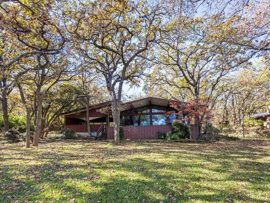 Old School Cool! A 1,550 Square foot weekender Cabana on 5.485 heavily treed acres with huge waterfront and newer dock, Azle side of the lake, north of Peden Road. The value here is almost exclusively in the land, but the cabana is your lagniappe, with a retro cool vibe, and a remodel by noted Fort Worth Architect Al Komatsu and Associates (plans available).

Enjoy the weekender while you create plans for your next waterfront palace or primary home! Then it becomes a guest cabin for friends and family! The sea wall is in fabulous shape and features a boat ramp beside the newer covered dock with one boat slip, ski doo rack, and Trex deck walkway and decking. A three-bay garage provides storage options for boats and vehicles further up the driveway, while a whimsical boat house on the sprawling green lawn provides storage for water toys, furniture, jet skis, etc.

Two lots total almost 5.5 acres and are heavily treed with mostly Post Oaks. Gradual sloping lush lawn and beach lead into the lake, easy access to the water for swimming or just floating around!!

Please note this is a survey of only one of the two lots, Buyer will need new survey. The property will be conveyed in As is, Where is condition.