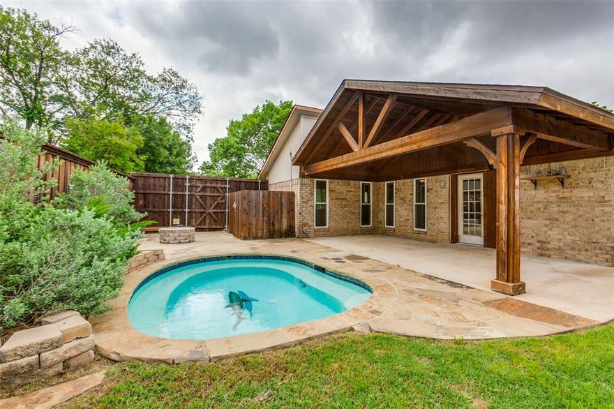 This inviting 3-bedroom, 2-bath home offers a light, open feel with vaulted ceilings, arched walkways, and extensive laminate wood flooring throughout. The family room centers around a classic brick fireplace, creating a warm and comfortable gathering space, while the kitchen features stainless steel appliances, granite countertops, and crisp white cabinetry that keeps everything feeling bright and clean. The primary suite includes a walk-in shower, and the two secondary bedrooms are generously sized with access to an updated shared bath. Step outside to a spacious backyard designed for entertaining, complete with a pergola-covered patio, sparkling play pool, firepit, storage shed, and a board-on-board privacy fence with plenty of yard space left. While technically in Dallas, the location sits right near Carrollton with a voluntary HOA and quick access to major highways, making commutes to downtown Dallas, Plano, and DFW Airport quick and easy.