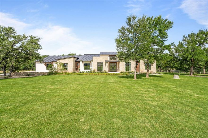 This modern Texas Hill Country-style home combines indoor and outdoor living in Rancho Ladera’s secure, gated community. Set on over two acres, this home exudes sleek design, luxury finishes and scenic views. The large living area has beautiful wood floors and striking fireplace. The kitchen boasts top-tier appliances, built in fridge, spacious island, and a walk-thru butler’s pantry with ample room for prep. The primary suite has ample light, a large ensuite with custom tile, dual vanities and closets and huge shower. Two other bedrooms each have their own ensuite baths. Near the main living area is a stately home study with built ins. The secondary living room has high ceilings, a wet bar with ice maker and powder room. Outside a covered patio and built in grill extends the living space and makes for ease of entertaining. There is a 3-car garage and room for extra parking.