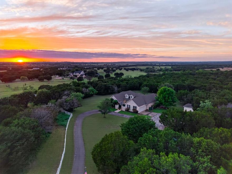 Discover a rare 15+ acre sanctuary nestled in the rolling hills of Granbury—America’s #1 Best Historic Small Town. Located on the desirable Acton side, the drive is defined by a landscape of green pastures and quiet ranches that makes the property feel worlds away while remaining remarkably accessible. Tucked into a private, one-entry pocket neighborhood, your future homestead is secured by a gated entrance and a long approach framed by mature cedars. Beyond the charming, old-world courtyard and cerulean blue French doors lies a home defined by joyful intentionality. This is not a cookie-cutter new build; it is a home with genuine character, charm, and endless possibilities. With high ceilings, transom windows, and an airy floor plan, the custom construction offers a perfect canvas. The heart of the home is a whimsical kitchen featuring signature pink cabinetry with delicate floral knobs, a custom wood-slab peninsula, open shelving, and a deep farmhouse sink. The dining space and primary suite have been freshly painted, adding a bright, updated feel to the home’s fabulous bones. Outside, you can watch the sunset from your 'Texas-sized' back deck or cool off in the above-ground pool—and don’t knock it till you’ve tried it; Texas summers get hot, and you won’t mind the setup when you’re floating in the water with nothing but trees and sky in sight. This property is a ready-made setup for the right owners to come in, add their own thoughtful additions, and truly create a special hobby farm. The infrastructure is already in place with a producing chicken flock, an Ulrich-built two-stall horse barn with a dedicated tack room, a private water well, and two beautiful pastures in the front ready for your vision. Also included are Beau and Belle, the Great Pyrenees working dogs. They are a valuable asset to land like this as proven guardians who fend off coyotes and other predators, ensuring the safety of the flock and the peace of the property.