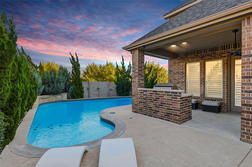 Located in the desirable Harvest community in Argyle, this impressive corner-lot home sits on a premium oversized lot and features a custom pool with dual water features, a diving pedestal, and a fully equipped outdoor kitchen designed for entertaining. The backyard includes upgraded landscaping for added privacy and a new roof for peace of mind. Inside, the home showcases over $80,000 in builder upgrades and additional custom improvements. The open-concept layout includes a media room with wet bar and powder bath, concealed theater wiring with Dolby Atmos surround sound, and built-in speakers in the family room and covered patio. The kitchen features upgraded cabinetry, granite countertops, herringbone backsplash, stainless steel sink, pot filler, and a butler’s pantry with coordinating finishes. Additional highlights include brackish-stained hardwood floors, wrought iron balusters, a raised-hearth fireplace with leuders stone and cedar mantle, and a mudroom with built-in bench. The three-car tandem garage features a professional epoxy and polyaspartic floor coating. The primary suite offers painted cabinetry, upgraded granite, a soaking tub, and elegant tilework. Throughout the home, you’ll find plantation shutters, upgraded lighting, ceiling fans, hidden TV wiring, neutral paint, and eight 4K CCTV cameras surrounding the home. Smart home technology controls the thermostats, lighting, pool, cameras, doorbell, and locks through convenient apps, and a fully paid security system monitors every window and door. The Harvest community offers multiple pools, a fitness center, coffee shop, parks, and walking trails, with convenient access to major highways, shopping, and dining, and is zoned for Argyle ISD.