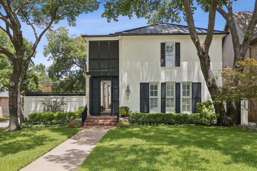 At 3036 Westminster Avenue, architecture tells a story of Charleston charm reimagined for University Park. Double piazzas stacked in perfect proportion frame mature trees along this quiet street. Reclaimed Louisiana Long Pine floors bring texture and history, refinished to lustrous warmth throughout. In the dining room, hand-applied Venetian plaster catches light like old European walls, creating depth paint never could. The grandest of three fireplaces draws you into the living room, where soft light and detailed woodwork feel reminiscent of simpler times. The masterfully remodeled kitchen reveals handcrafted cabinetry in Charleston Green set against exposed brick archways, while new surfaces and professional appliances serve function with fanfare. The generous walk-in pantry and refrigerated 120-bottle wine room add ease to entertaining. Two distinct garden courtyards — one brick, one slate — bracket a custom outdoor fireplace anchoring evening gatherings. The fountains, one replaced in 2024, provide gentle auditory backdrop transforming the yard into a haven. The upstairs screened porch — a full-length outdoor room — connects private quarters while offering treetop views. It leads to the garçonnière, providing flexible space for guests, office, or creative retreat. The generous primary suite features its own fireplace and newly renovated bathroom with Italian Porcelain walls, a floating mirror, and bronzed hardware grounded by custom teak cabinetry. Bespoke millwork in reimagined his and hers closets elevate storage into quiet indulgence. The new standing seam metal roof speaks to permanence. Upgraded lighting, new plantation shutters, 20-foot garage ceiling, built-in storage, whole-home Sonos system and security enhancements show how heritage and technology coexist gracefully. This address places you in Dallas' most coveted quadrant, where tree-lined streets connect to Snider Plaza's upscale dining and boutiques, with vibrant city center minutes away.