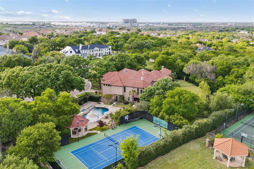 Exuding timeless elegance, this Mediterranean Spanish style revival estate rises as a rare expression of Old-World artistry and luxury, where every detail has been curated to evoke the feeling of a private European villa set within an exclusive Texas sanctuary. The residence rests on 2.214 acres of land in the prestigious King’s Gate neighborhood. The estate is positioned on a commanding homesite, capturing sweeping greenbelt vistas and unforgettable sunset skies. From the moment of arrival, the architecture reveals itself with quiet grandeur, arched forms, hand-finished detailing, and a sense of proportion that feels both timeless and intentional. The residence offers 6 bedrooms, including a private casita suite designed for guests or multigenerational living while thoughtfully separated with a stone fountain courtyard. Inside the home transitions into a world of refined interiors and layered craftsmanship. The first-floor executive study is a statement of quiet sophistication, framed by arched windows, enriched with detailed millwork, and a fireplace that anchors the space in warmth and tradition. Within, a dedicated golf simulator lounge offers a rare and refined amenity for enthusiasts, perfectly complemented by an outdoor putting green for year-round enjoyment. Wellness and recreation are thoughtfully woven into the estate, with a full exercise room, and a private tennis-basketball sport court. A 5-car garage with one bay thoughtfully converted into a wellness space. Below, hidden within the architecture of the home, a climate-controlled wine cellar awaits, wrapped in natural stone and rich wood finishes. Behind arched iron doors, curated wine displays unfold in an atmosphere reminiscent of a European estate tasting room. The outdoor grounds feature a resort-style pool with a gazebo, and lush landscaping. Every space has been composed to deliver a sense of permanence, privacy, and elevated living, an estate that is not simply lived in, but experienced.