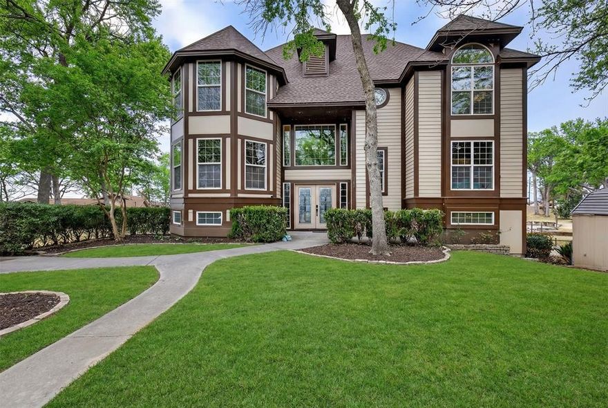 Castle like 3 story waterfront retreat located at the mouth of the channel, offering weather protection at the boat dock and amazing open water views from all over the house! Outside there is extra driveway space for huge family functions, two covered back porches, and a jacuzzi for unwinding after a day on the lake. Inside you will find soaring ceilings with tall dramatic windows, a striking double-sided fireplace anchoring the main living spaces and creating a warm inviting ambiance for lake retreat style entertaining. There is a dedicated office space and flex room. The primary suite is nothing short of stunning with a walk out water view balcony. Large spa like on suite with a huge jacuzzi tub and separate shower. The basement level of the home offers full guest living quarters with its own bedroom, full bath, full kitchen, and living area. You will find a full workstation with shelving and sink in the oversized garage. Lots of storage space with a huge walk-in pantry off the kitchen and dedicated laundry area in the basement with sink, cabinets, and shelving. Fenced in nice sized yard and boat dock with party deck, boat cradle replaced about a year ago. The roof was replaced about 4 years ago. This home blends timeless architectural charm and lake life living with plenty of space for the whole family.