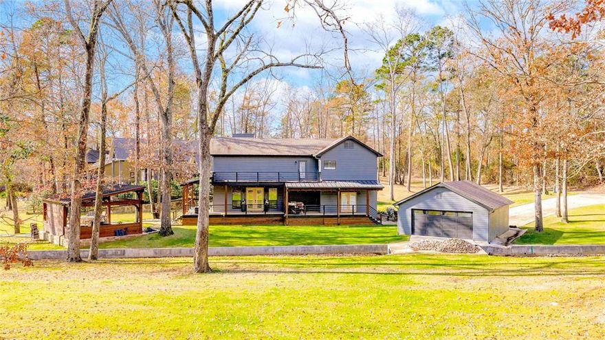 Welcome to this idyllic 3 bedroom, 4 bath waterfront retreat perfect for weekend escapes or full time lake living filled with relaxation and fun. A spacious wraparound porch sets the scene for morning coffee, sunset dinners, and memorable gatherings. Inside, the home impresses with rich wood flooring, soaring wood-plank ceilings, fresh interior paint, and a designer tile backsplash. The expansive second floor loft overlooks the main living area and serves as a versatile game room or additional bunk space for guests. Situated on a generous 1.26 acre lot, the property offers ample room for outdoor activities and includes a family sized cabana ideal for entertaining and lake life lounging. The boathouse has been cosmetically updated and features two slips with new lifts, along with abundant storage for water toys and gear. The fully sodded yard with Crown Zoysias is supported by a full sprinkler system with automatic timer, while a concrete walkway leads to a cozy fire-pit area perfect for cool evenings by the water. Extensive drainage improvements have been completed to ensure proper water flow across the property to the lake after a rain shower or storm, and a 27 KW Generac propane generator adds peace of mind. A rare two-car garage for a lake home provides additional convenience and storage. Outdoor cameras covering the entire property gives you added security and safety. An added bonus is the Mist Away system on all structures keeping the bugs away! This truly is a little slice of heaven on the water ready to be enjoyed.