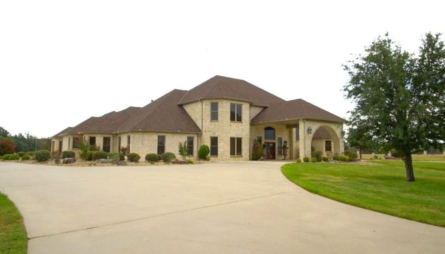 Grand, executive stone home, 253 acres of ranch land, 10+ acre lake with concrete walk around, elaborate cabana, pool house, outdoor kitchen. Waterfall pool with slide, spa area, 60x100 finished shop, 30x60 metal hay barn, 1000+ feet concrete driveway and bridge entrance. 4000+ feet of lighted decorative steel and stone fencing, driveways, immediate grounds. 5000+ feet of steel fencing along 3 road frontages and 80-foot pier with 20x20 gazebo. Home is 4 bedrooms (or 3 and a media room). 4 and a half baths, grand garden tub primary suite, multiple living areas, palatial dining, equipped work island kitchen and high-end finishes and amenities throughout. Includes 3-bedroom rent house (south of entrance), $650 per month income.