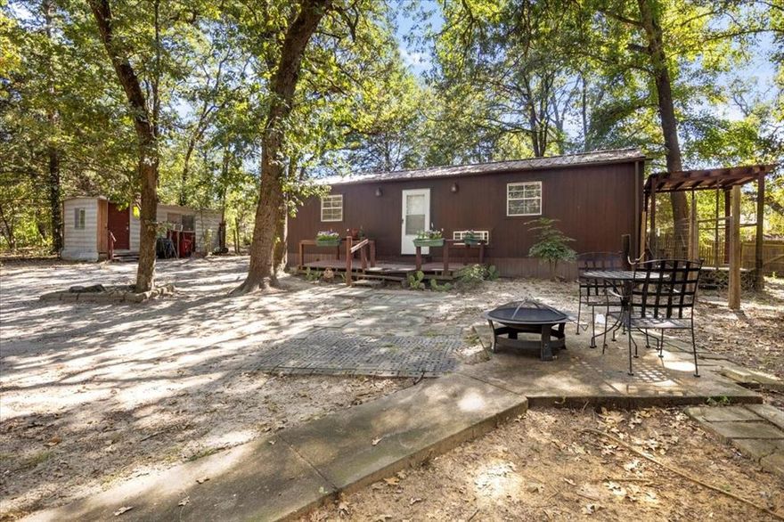 Charming rustic cottage with 1 bedroom, 1 bath. Nestled among the trees with fully fenced .40 acres and gate for privacy. Home has full kitchen with electric cooktop, wood cabinets, refrigerator, open shelving and plenty countertop space. Outside, there are 2 porches to enjoy, 3 storage sheds - including a laundry shed that has a window unit, wood burning fireplace and room for man cave-she shed, storm shelter, firepit area with seating and property is cross fenced. LOW utility bills!