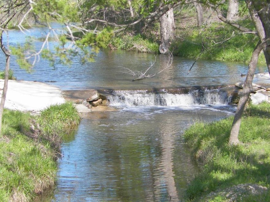 261.89 acres, ranch offers a blend of beautiful hills and ranching in the heart of Texas Hill Country. This property features approx. one mile of both sides of Wallace Creek and has diverse topography. Wallace Creek offers fun such as wading, swimming and fishing. Tree shaded banks and valleys offer park like settings for wonderful family picnics. Wildlife is abundant, Whitetail deer, Turkeys, Ducks, Feral Hogs. The ranch has 3 dependable stock tanks. There is a water well that supplies the house and headquarters area, another windmill well on the back side of the ranch and a water well for the main home. Ranch has two custom-built homes in 2007, total of approx. 6,224 sq. ft., combined 8 bedrooms, 5.5 baths. Designed with a breezeway, a large deck overlooking Wallace Creek, the homes have vaulted ceilings, 1 stone fireplace, wood floors, and high-end finishes. Close to the main house is a work shop or barn, concrete slab and a covered area for storage of tractors, equipment. The ranch has two entrances one for the main house and small shop and the other one is for the headquarters, farm house and large shop. Quaint farm house 100 +- years old has a screened-in porch, two bedrooms, full bathroom, and central heating and cooling making it a great ranch foreman quarters or a hunting cabin. A 40 ft. x 63 ft. approx barn has a slab, 2 drive-through overhead doors, 3 walk-through doors, insulated, electric, water and a bathroom laundry room. A small shed with AC behind the barn and across the road are pipe working pens and a squeeze chute. The ranch is cross fenced into several pastures allowing for rotational grazing. The large hill top with dense cover provides great hunting and has several great home sites with exceptional views. This is truly a combination ranch providing the best of both worlds for hunting, recreational and agricultural. The seller is open to selling the main house, small shop along with 30 acres or more.